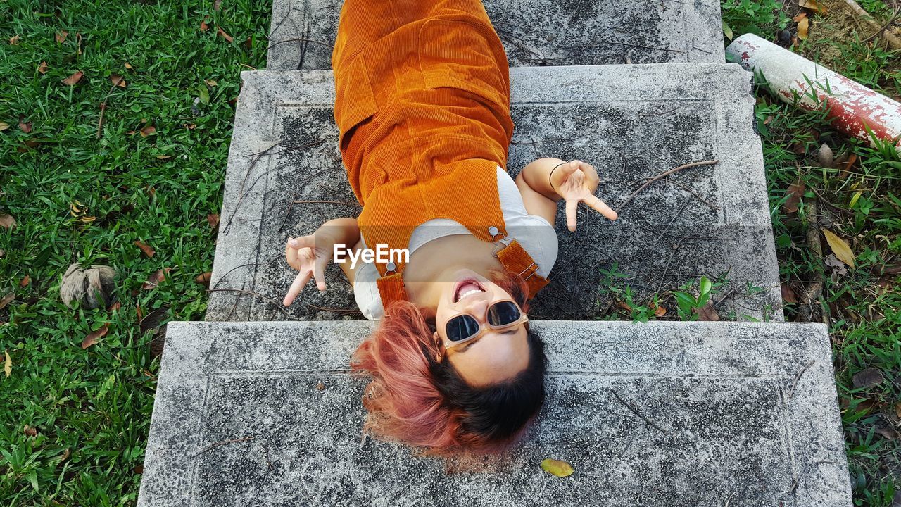 High angle portrait of young woman lying on steps