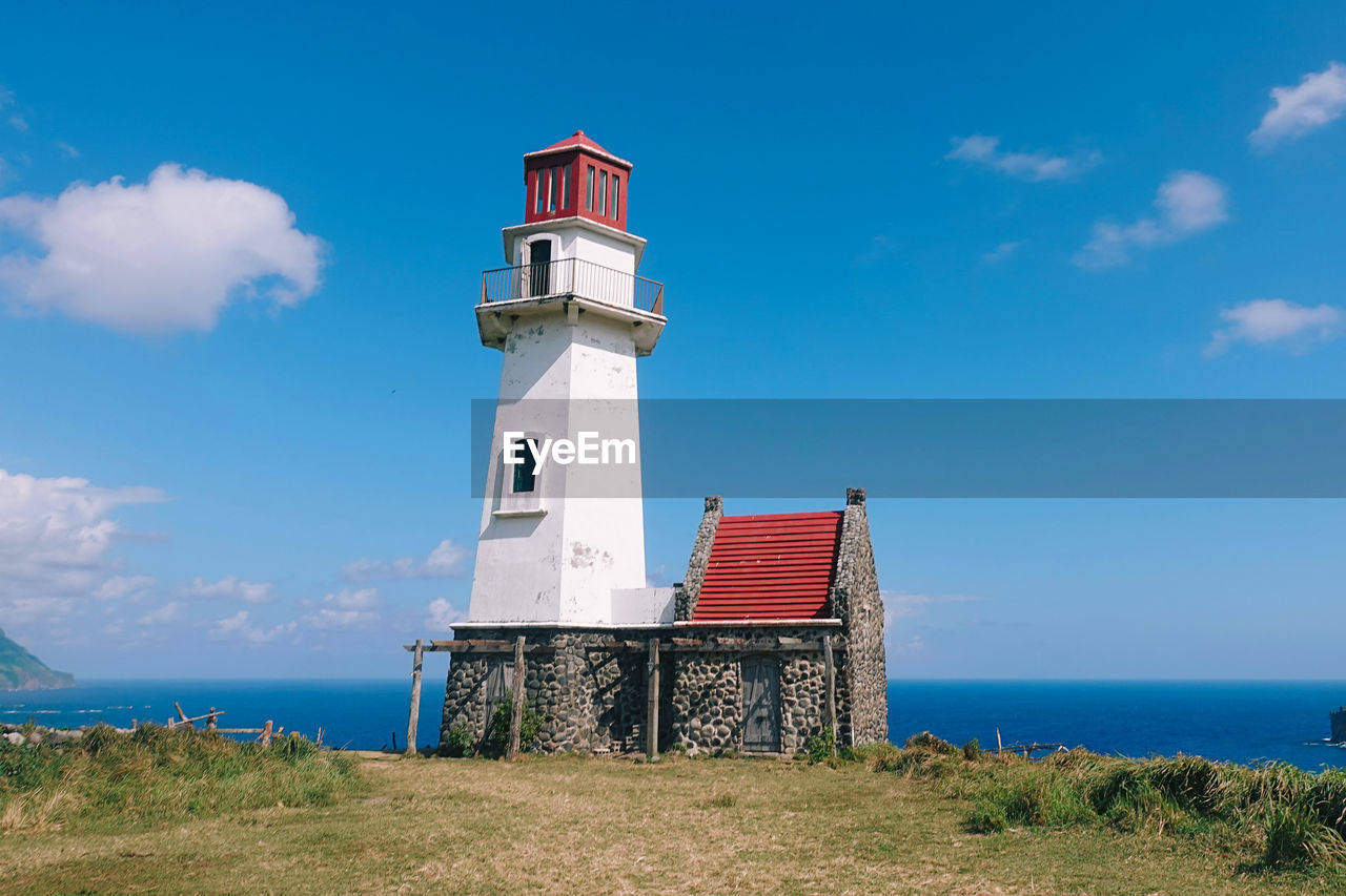 Lighthouse by sea against sky