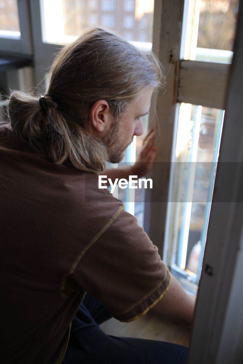 High angle view of man looking out through glass window