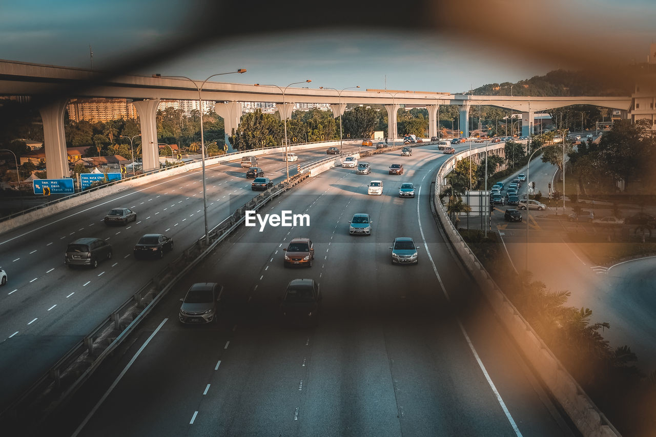 High angle view of cars moving on road seen through fence during sunset