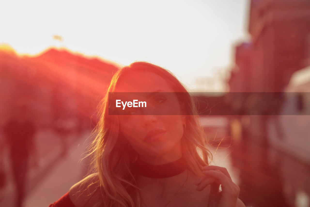 Portrait of young woman looking away against sky