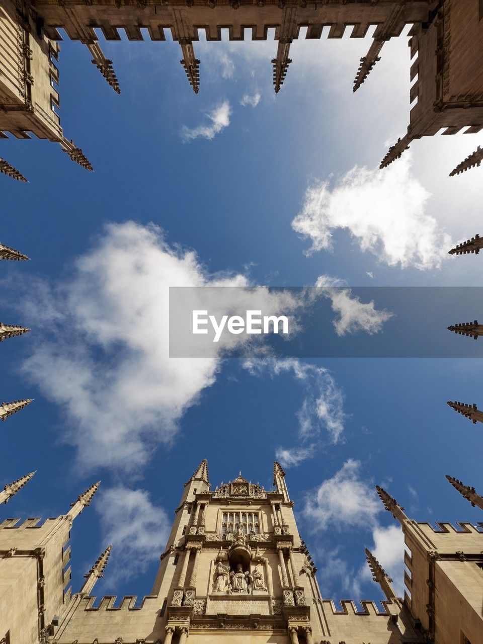 Low angle view of oxford bodleian library spires against blue sky with clouds