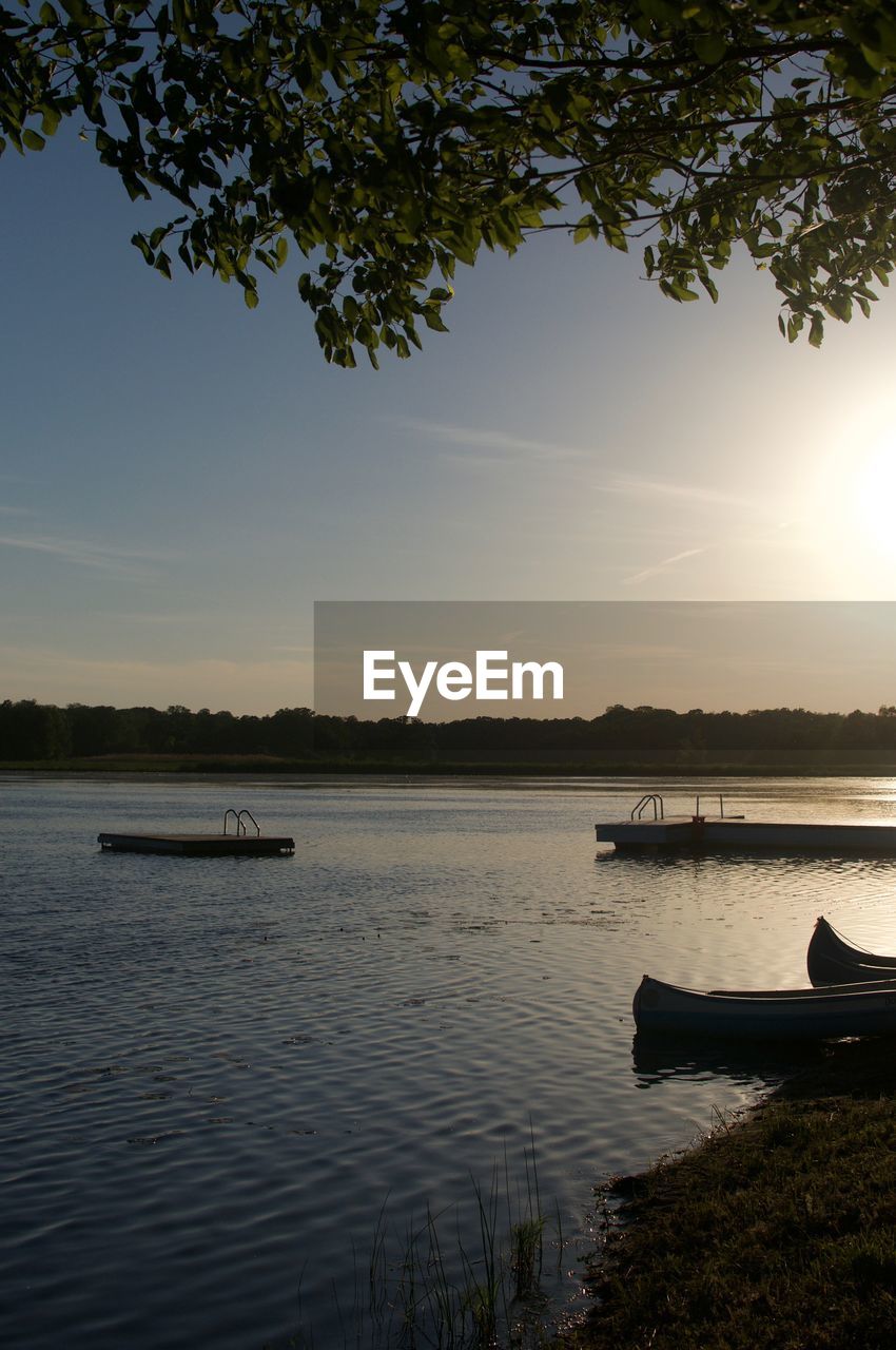 BOAT MOORED IN LAKE AGAINST SKY