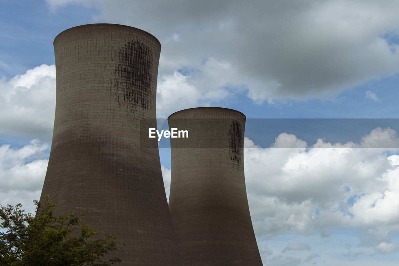 Two grey, industrial power station cooling towers and blue sky clouds