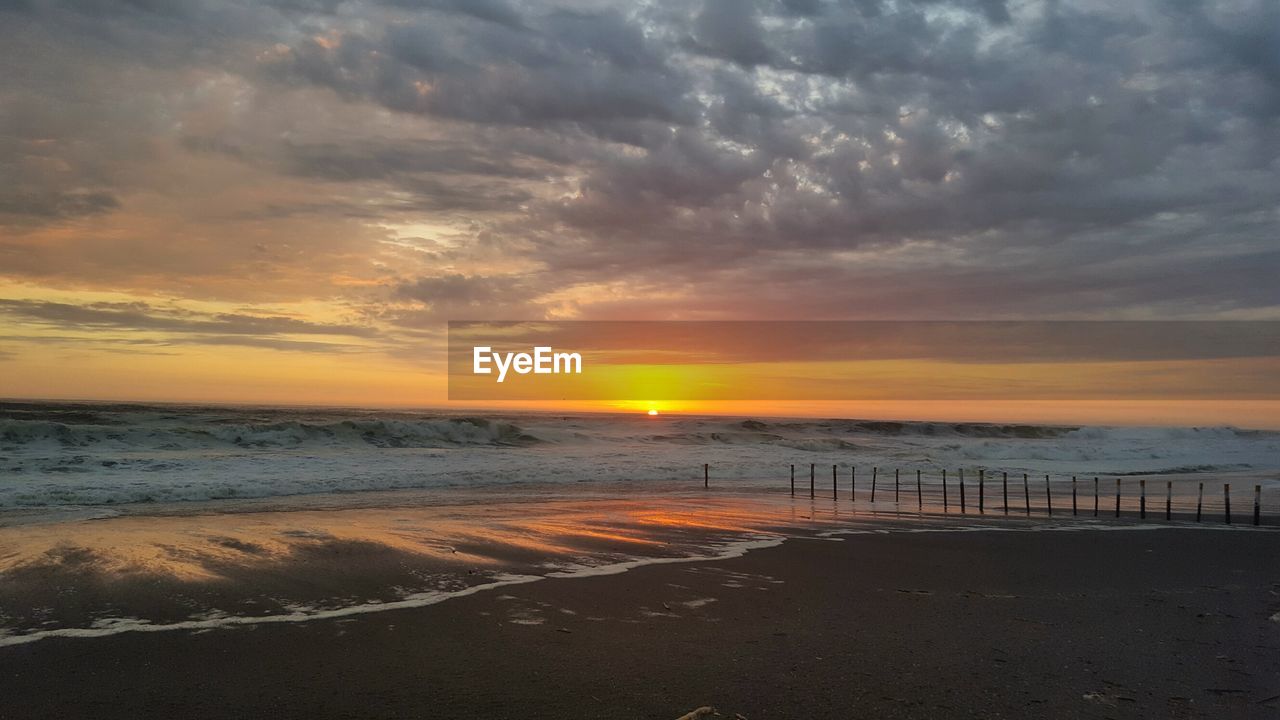 Scenic view of beach against dramatic sky