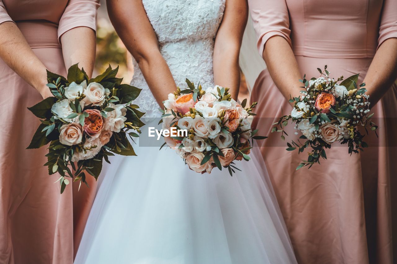 Midsection of women holding flower bouquets in wedding ceremony