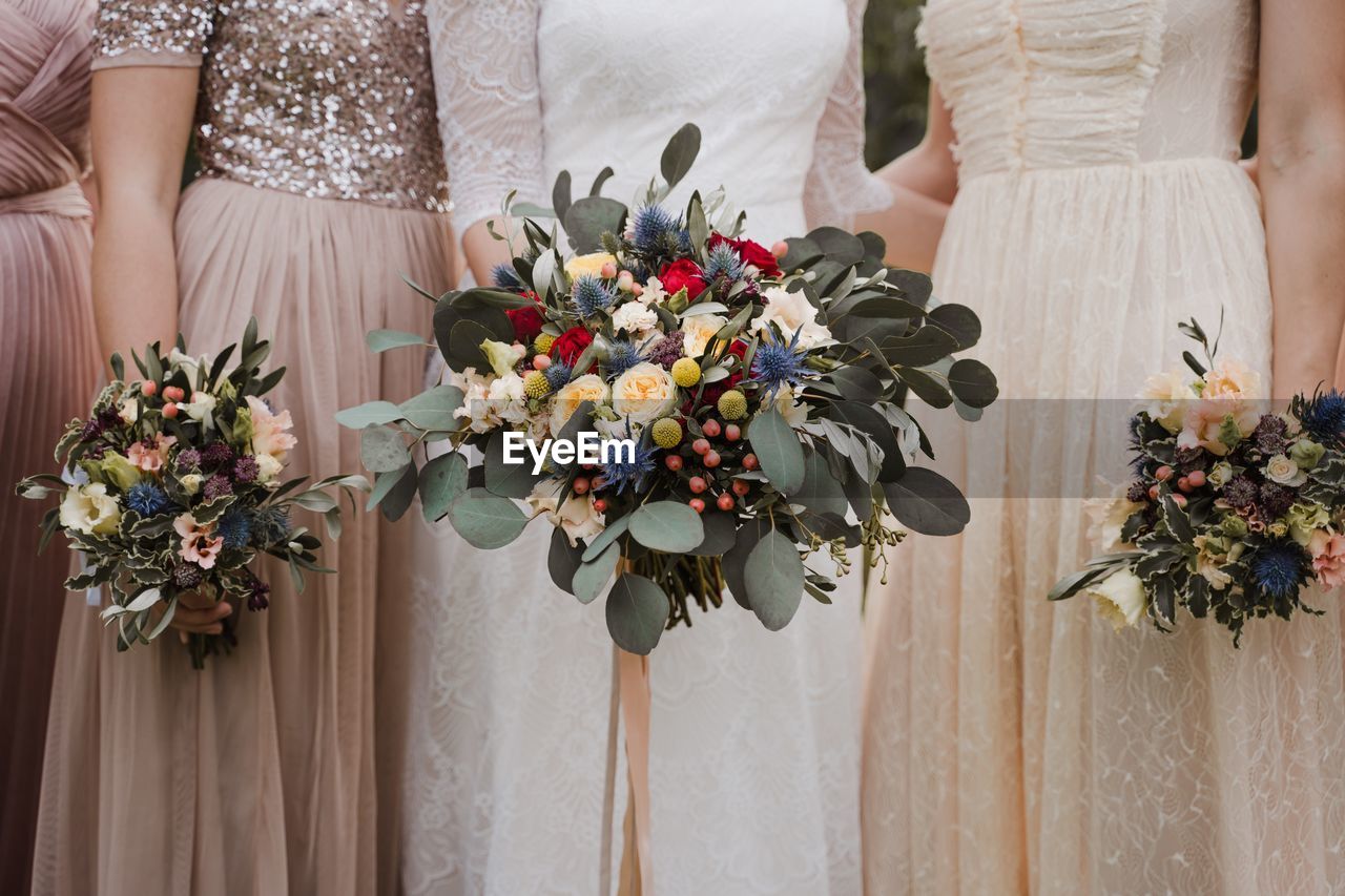 Bride and bridesmaids holding wedding flower bouquete in dress