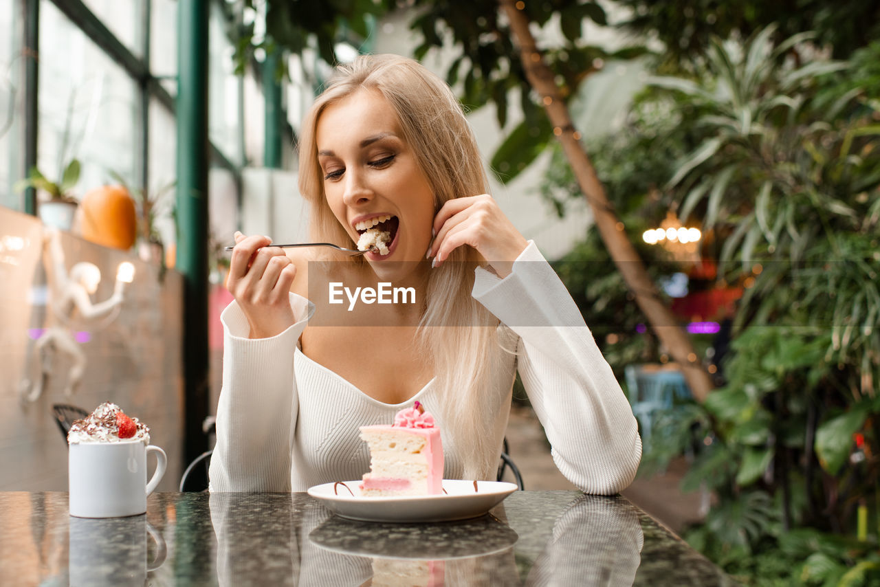 Portrait of young woman drinking coffee while sitting on table