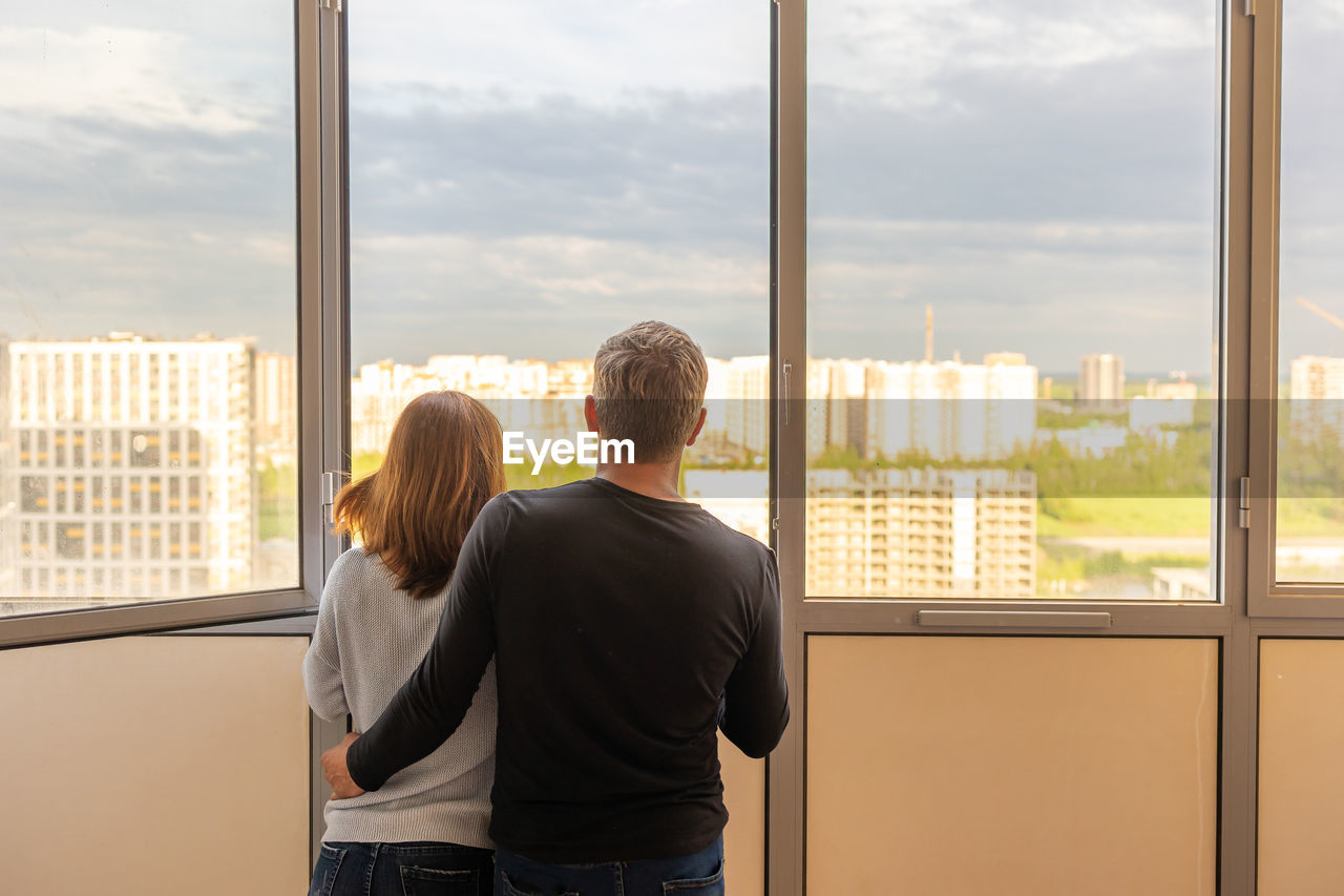 Man hugging his wife. young couple moving in new apartmen. people looks out window at new 