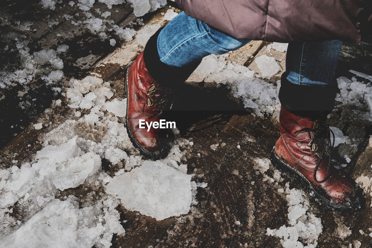 Low section of man walking on footpath with snow