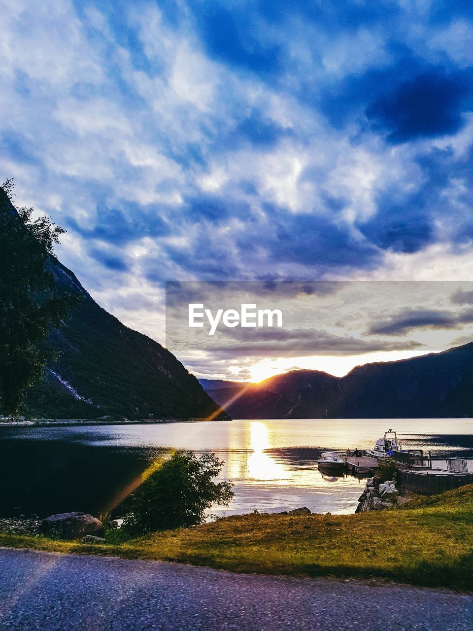 SCENIC VIEW OF LAKE BY MOUNTAINS AGAINST SKY AT SUNSET