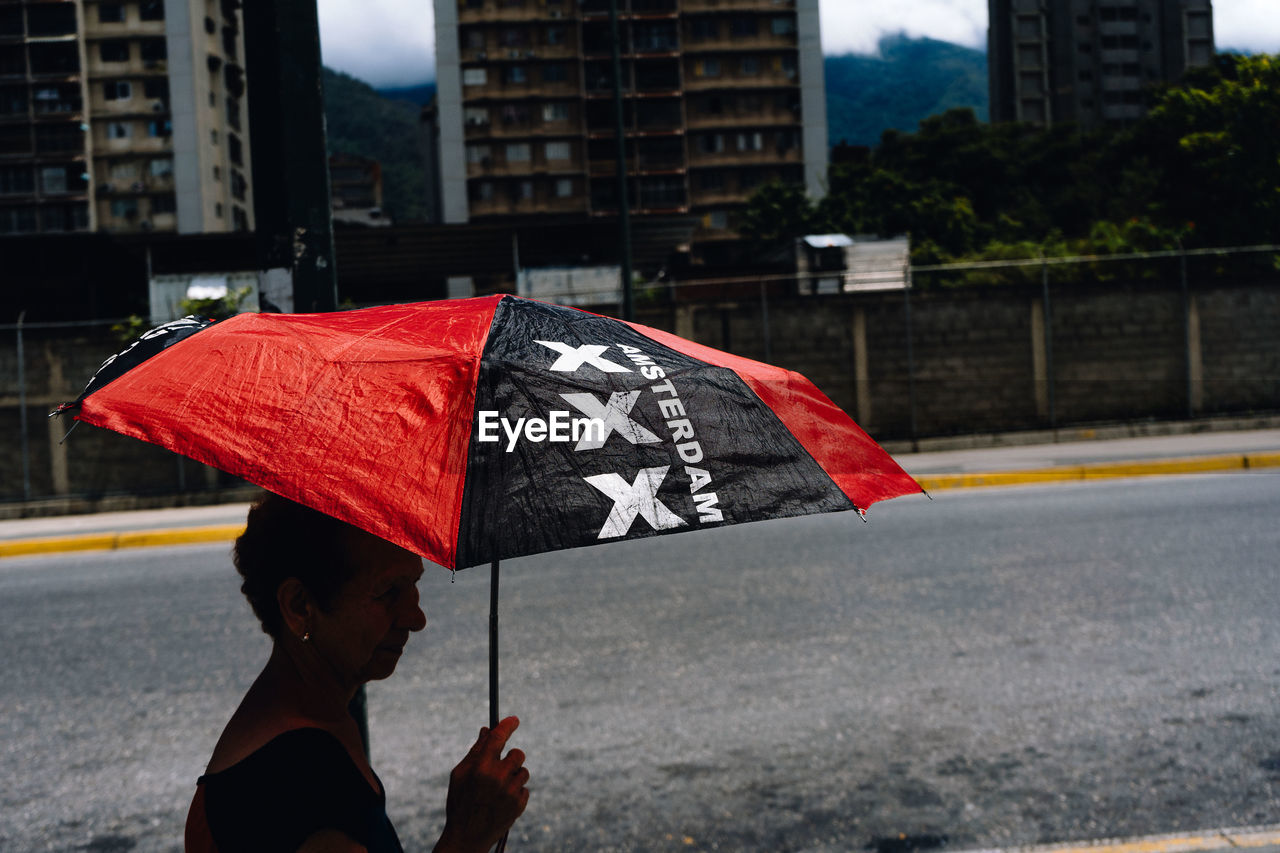 MAN HOLDING UMBRELLA ON STREET IN CITY