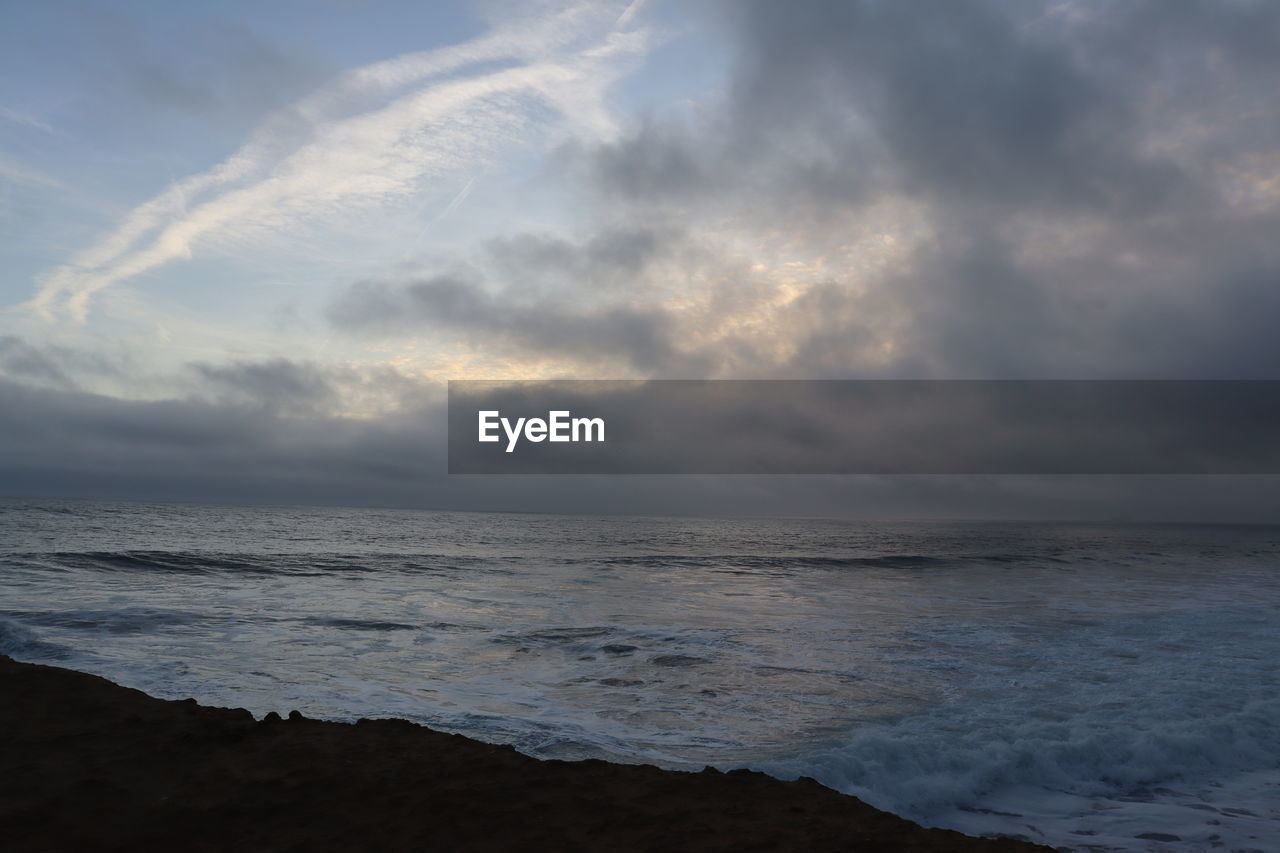 SCENIC VIEW OF BEACH AGAINST CLOUDY SKY