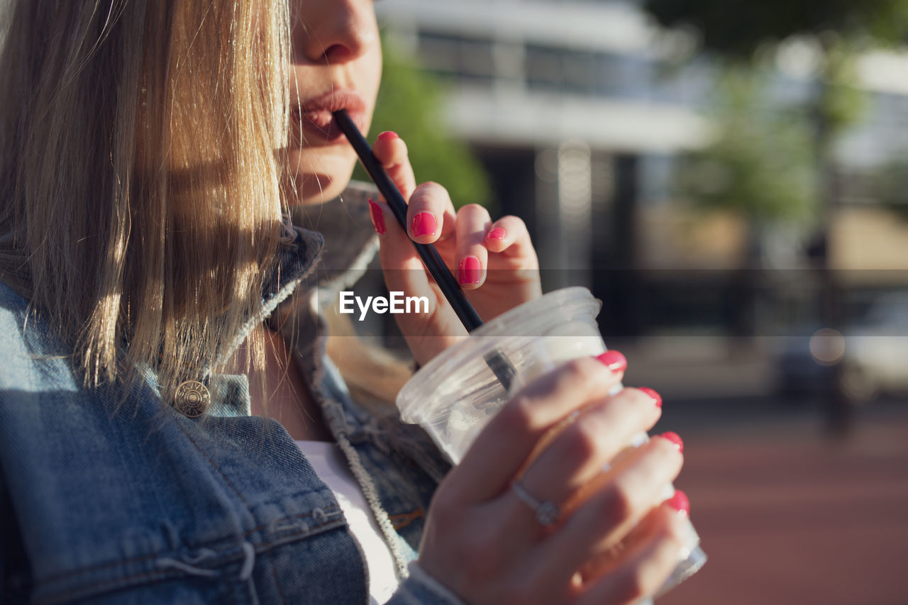 Midsection of woman drinking coffee in city