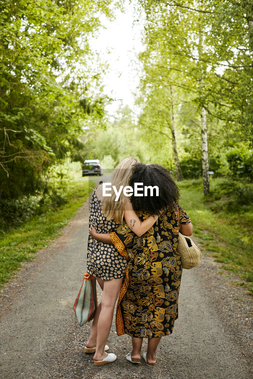 Two young women embracing on road