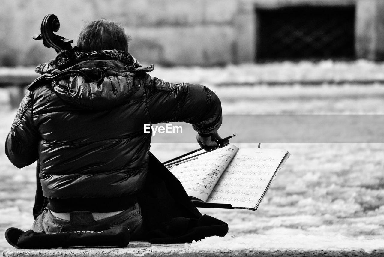 Rear view of musician playing double bass at street during winter