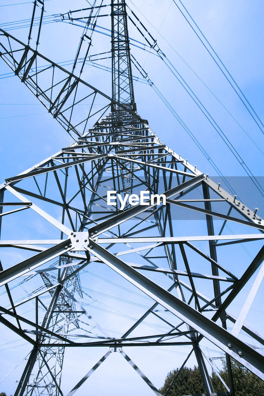 Low angle view of electricity pylon against blue sky