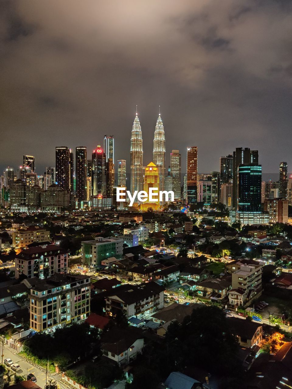 Illuminated buildings in city against cloudy sky