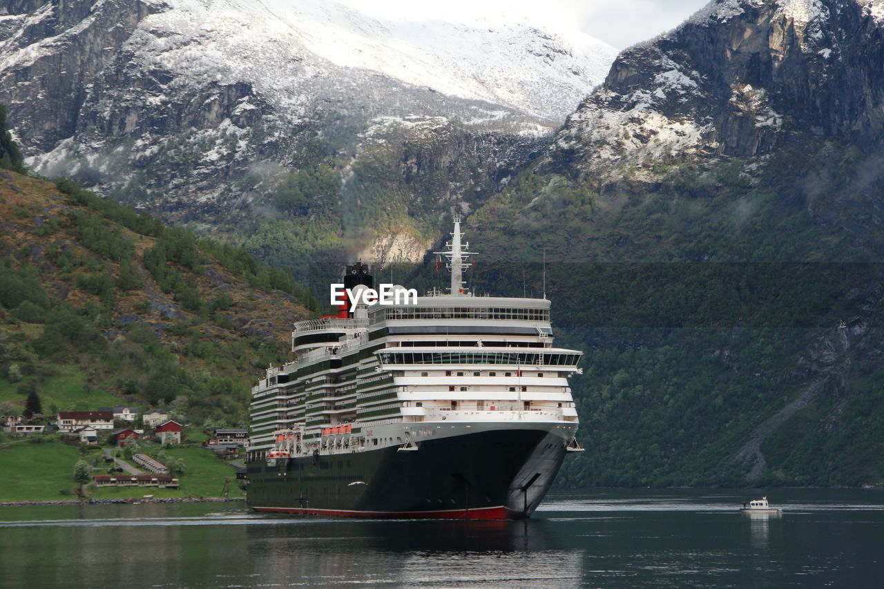 PEOPLE SAILING ON SEA AGAINST MOUNTAINS