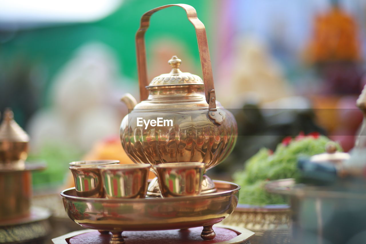 food and drink, focus on foreground, no people, household equipment, food, table, religion, teapot, close-up, kitchen utensil, tradition, spirituality, ceramic, container, belief, selective focus, outdoors, tea