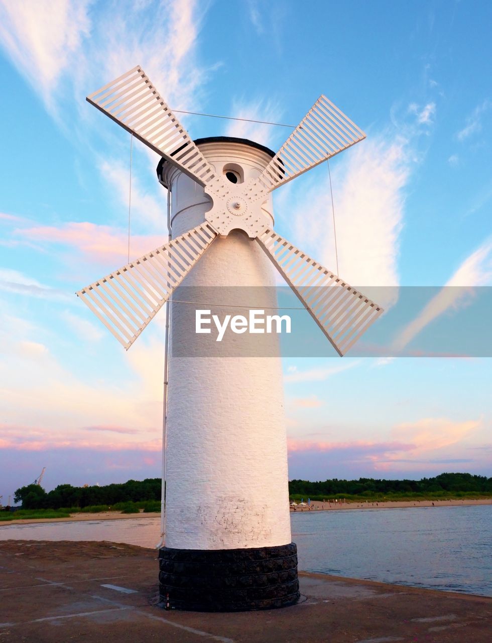 TRADITIONAL WINDMILL BY WATER AGAINST SKY