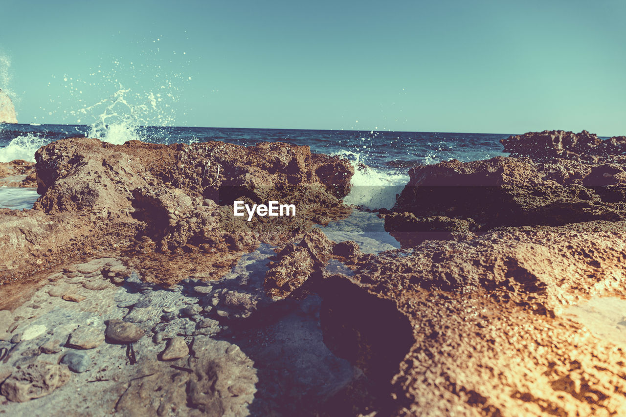 Close-up of rocks on beach against clear sky