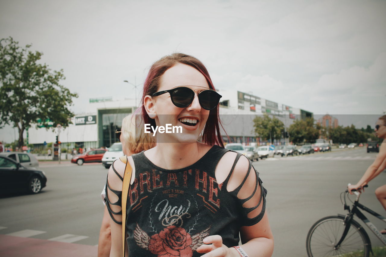 PORTRAIT OF HAPPY YOUNG WOMAN IN SUNGLASSES