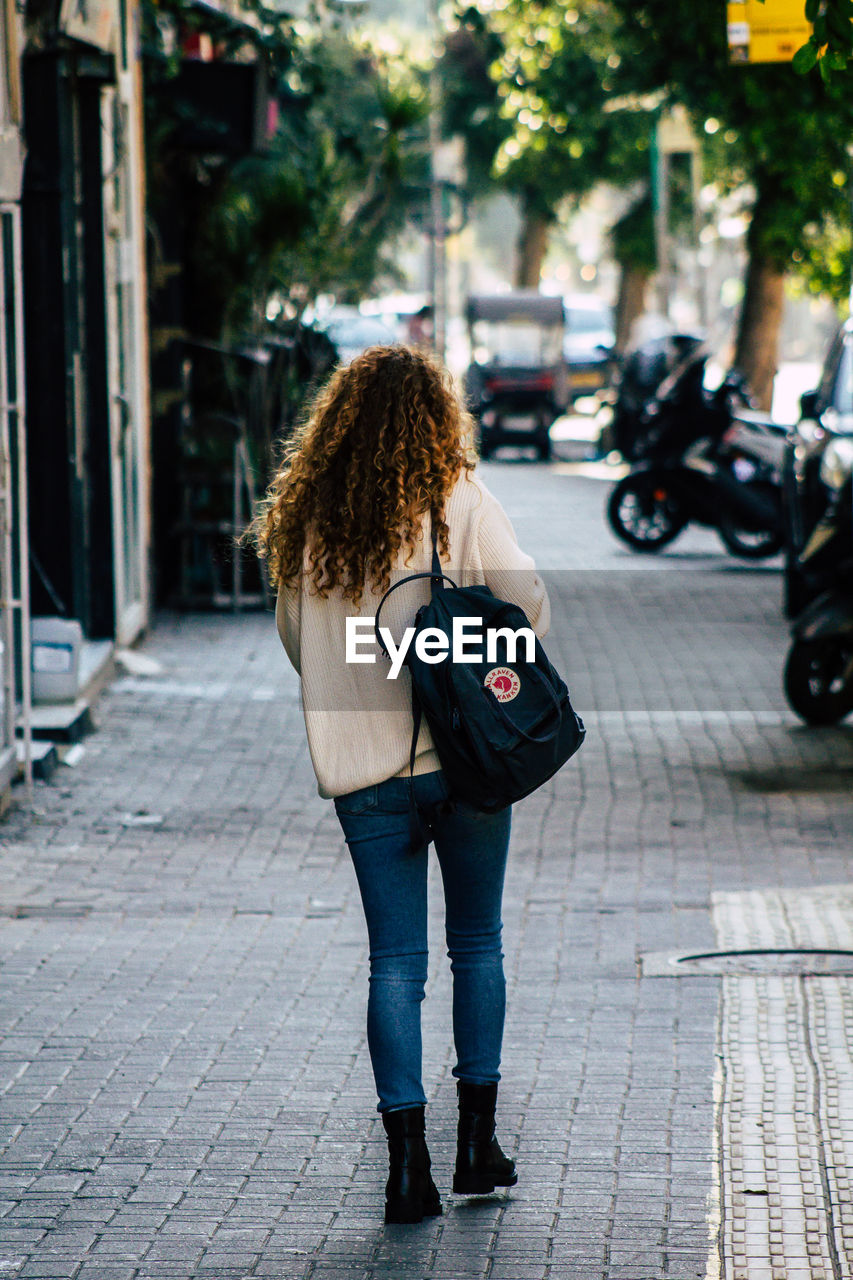 FULL LENGTH REAR VIEW OF WOMAN STANDING ON STREET