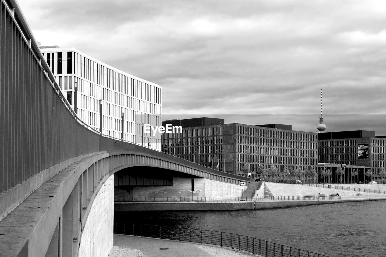 BRIDGE OVER RIVER BY BUILDINGS AGAINST SKY