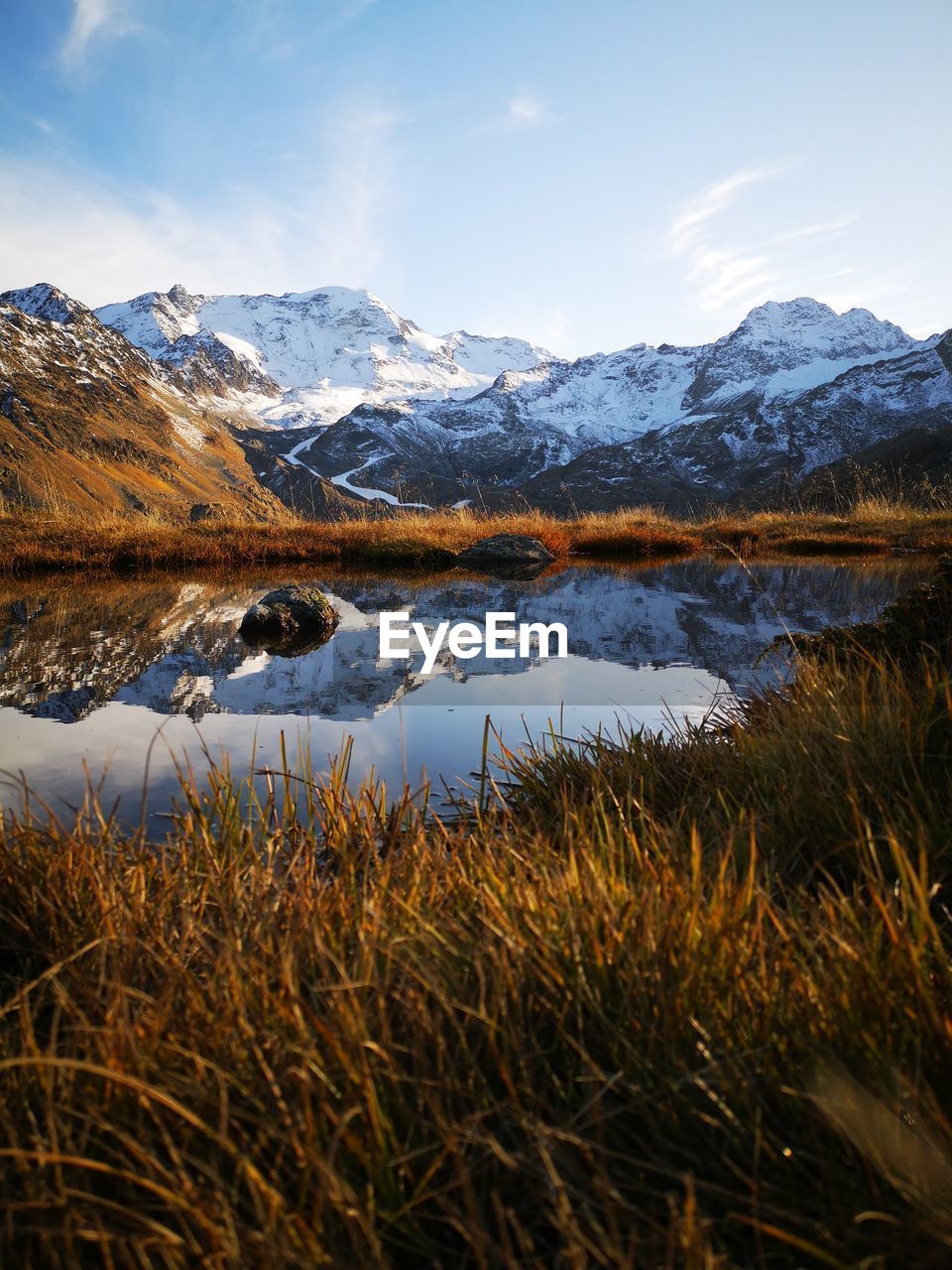 Scenic view of lake by snowcapped mountains against sky