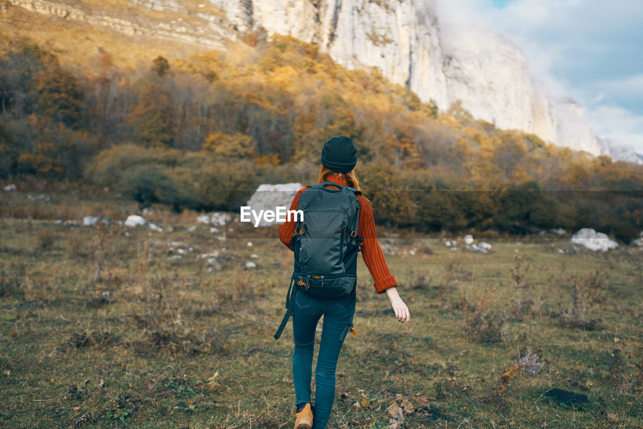 FULL LENGTH REAR VIEW OF MAN WALKING ON ROCKS