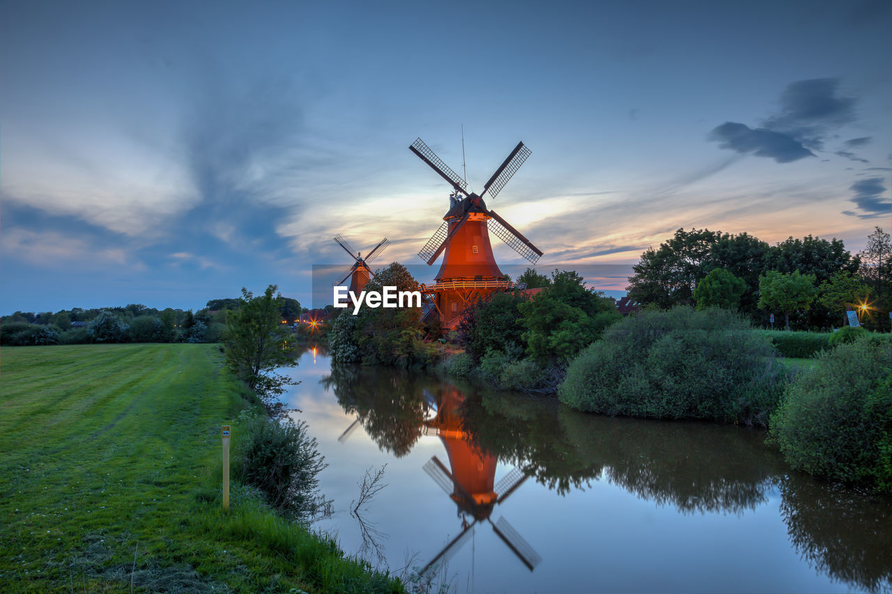 TRADITIONAL WINDMILL BY WATER AGAINST SKY