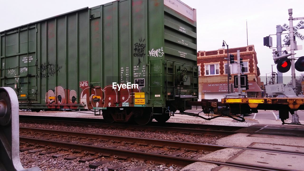 TRAIN ON RAILROAD TRACKS AGAINST SKY IN CITY