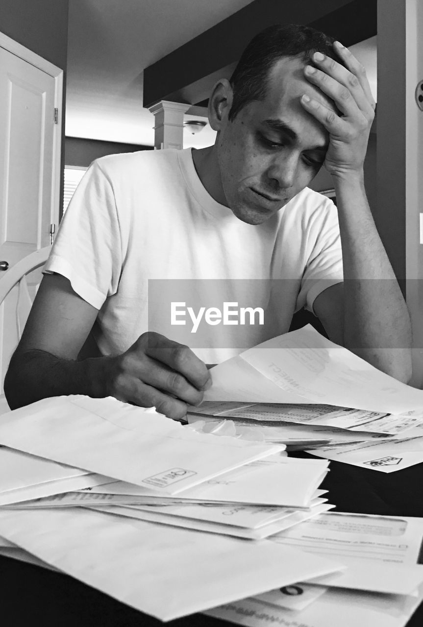 Stressed man with paperwork at home