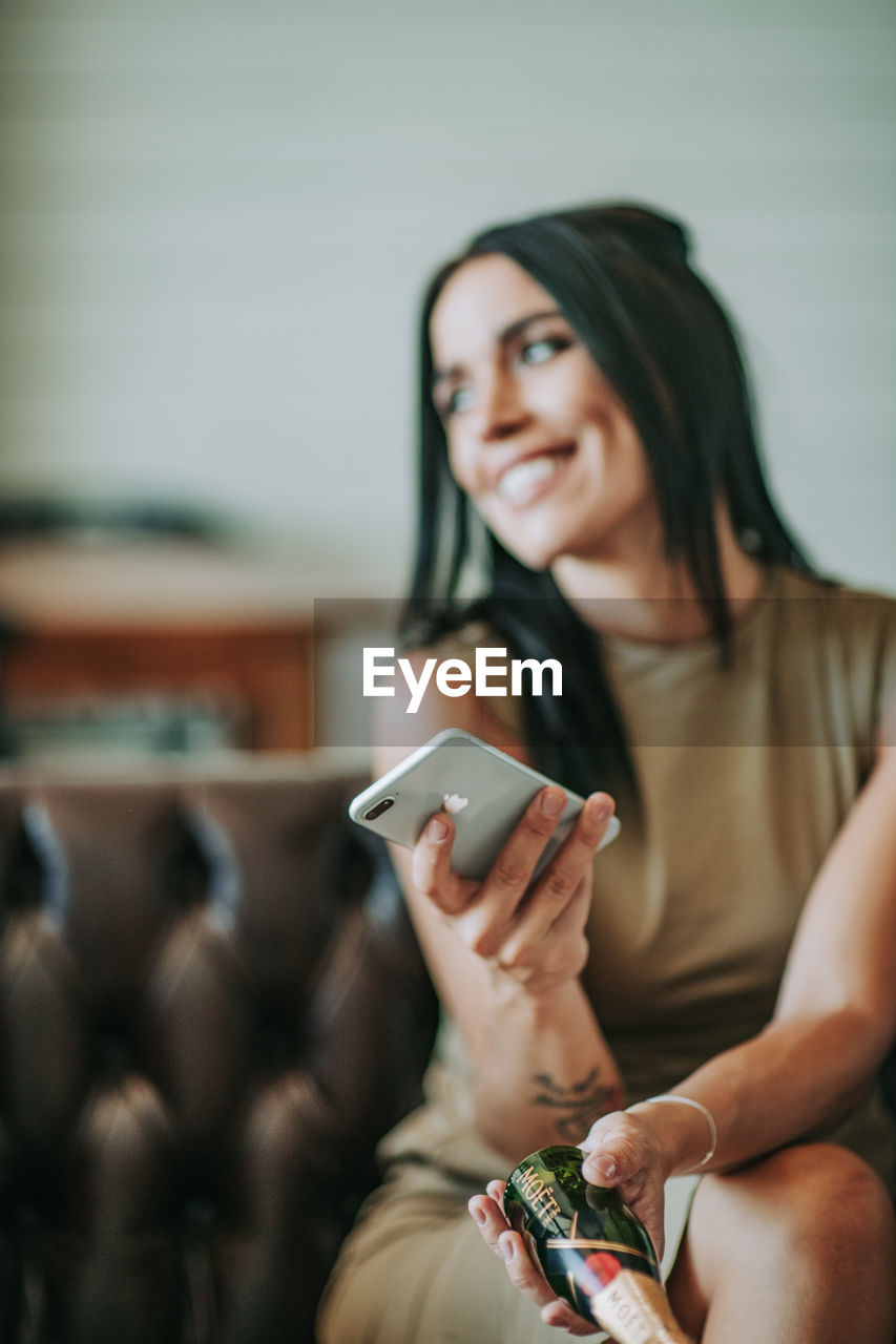 Woman with mobile phone sitting on sofa at home