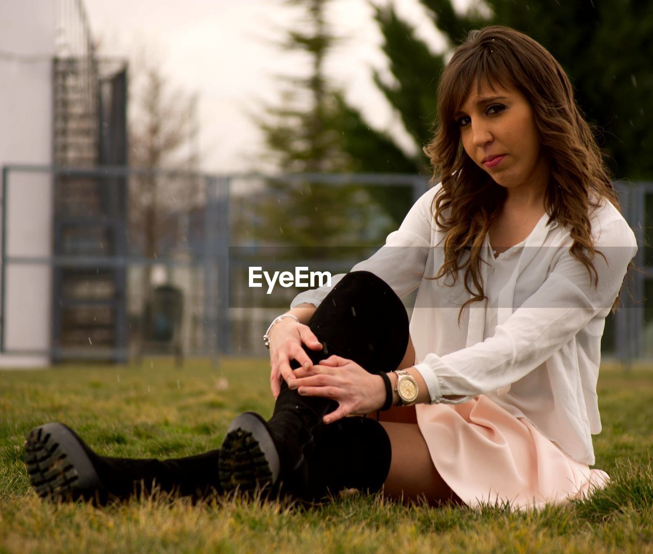 Portrait of woman sitting on grass against trees