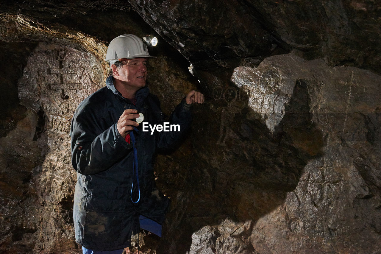 Man wearing helmet standing in cave