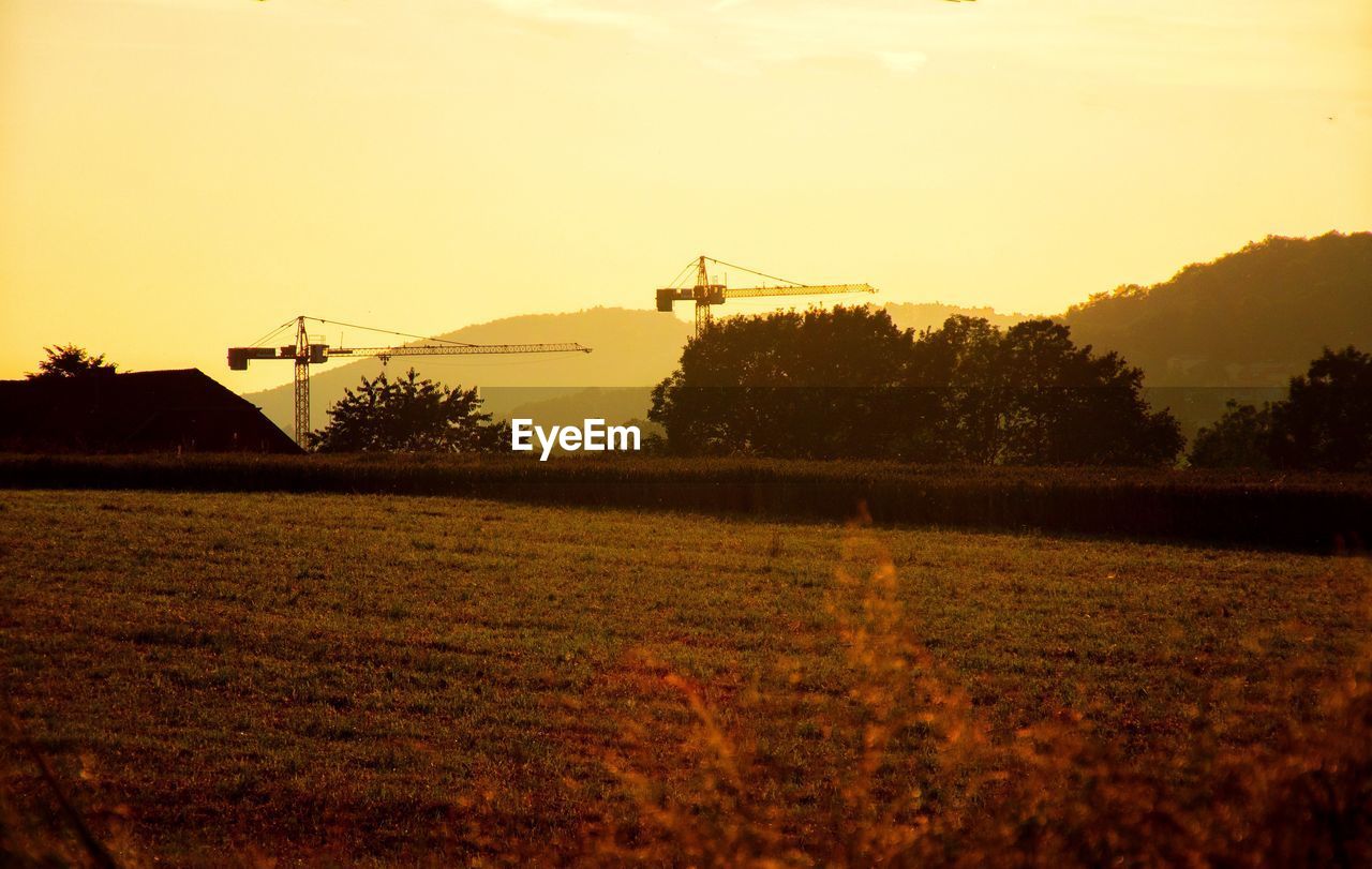 Crane on field against sky during sunset