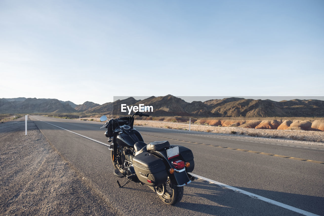 Motorcycle parked on desert road against sky, nevada, usa