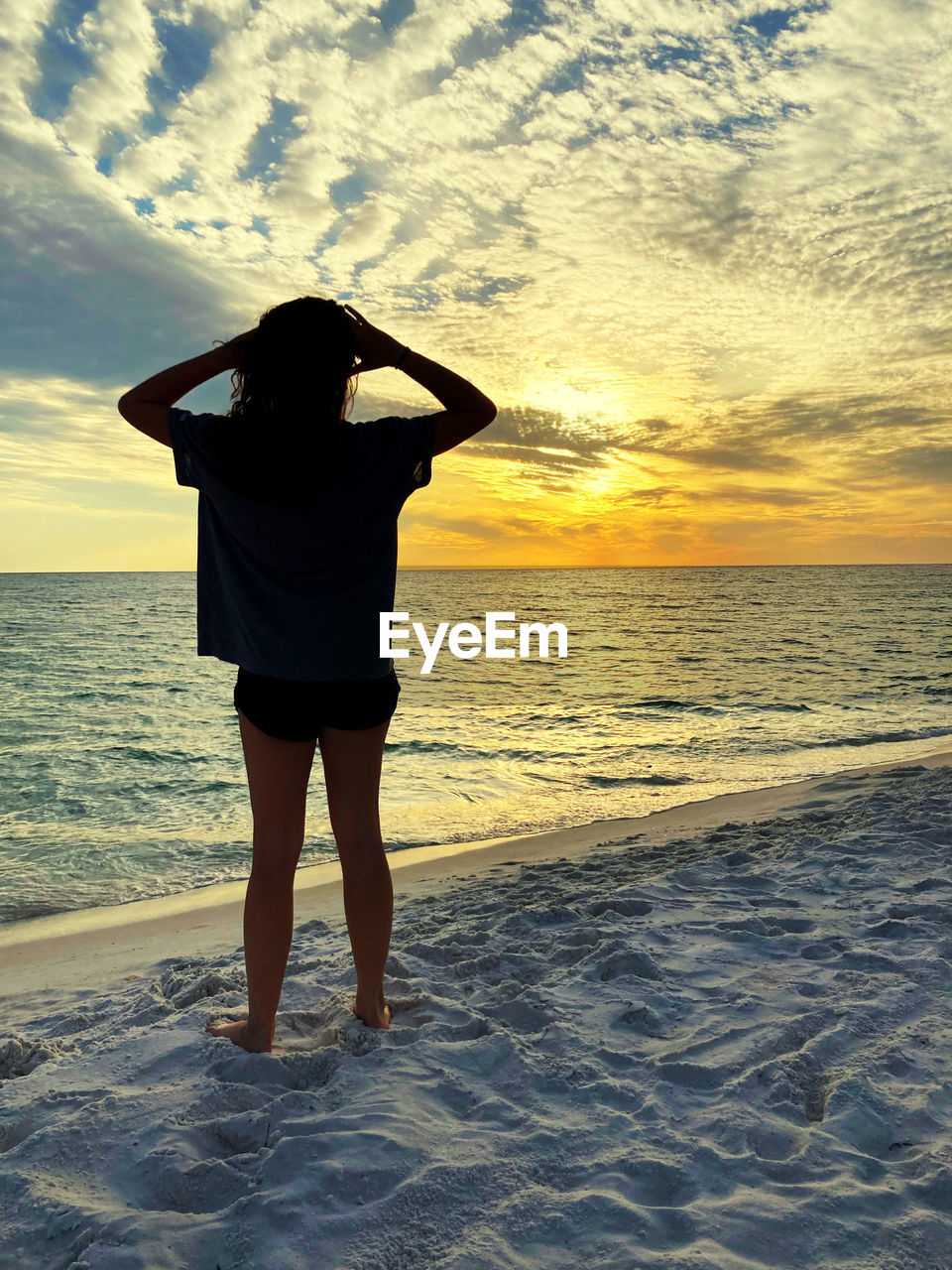 sky, sea, water, beach, one person, ocean, land, sunset, sunlight, horizon over water, horizon, nature, cloud, standing, rear view, beauty in nature, adult, leisure activity, vacation, shore, full length, trip, holiday, scenics - nature, lifestyles, coast, wave, sand, women, tranquility, idyllic, tranquil scene, outdoors, clothing, evening, relaxation, person, young adult, silhouette, casual clothing, solitude
