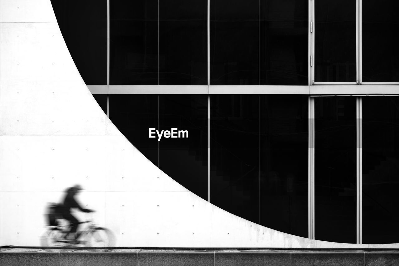 Blurred motion man cycling against building