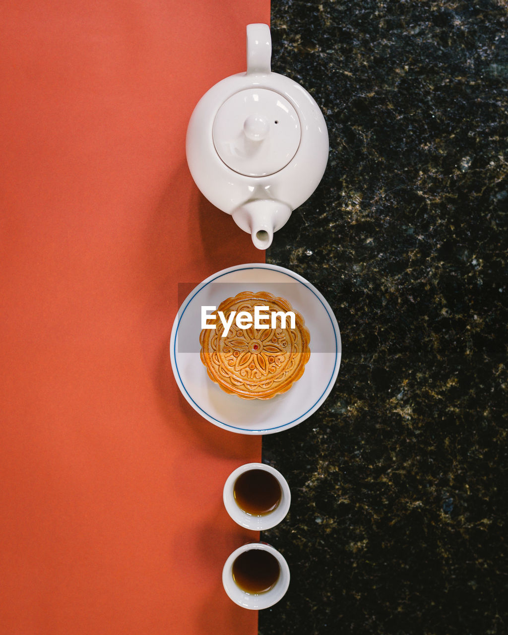 HIGH ANGLE VIEW OF COFFEE CUP ON TABLE AGAINST ORANGE WALL