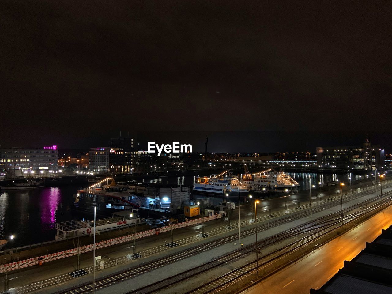 HIGH ANGLE VIEW OF ILLUMINATED STREET AMIDST BUILDINGS IN CITY