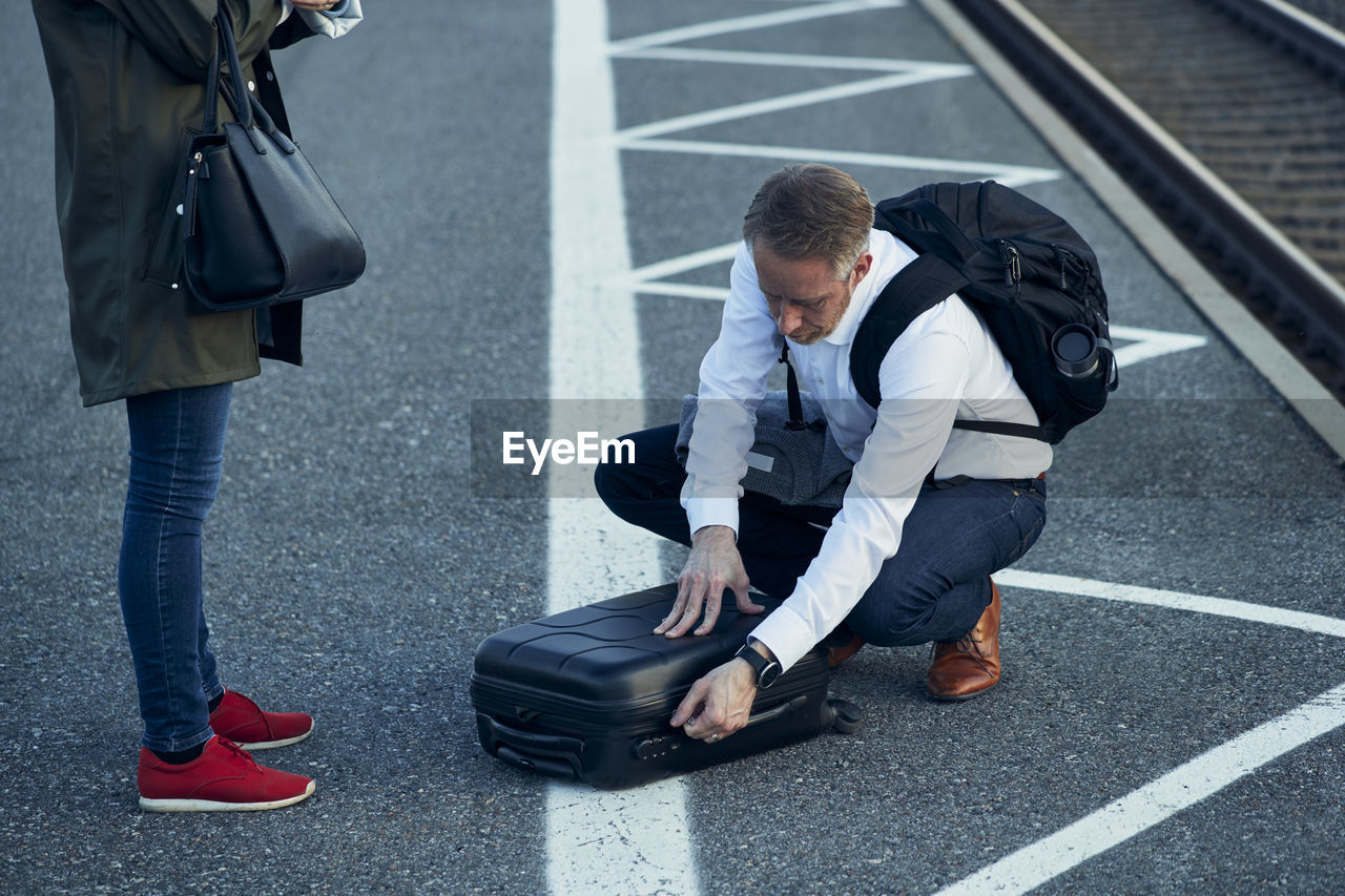 Man on train station opening suitcase