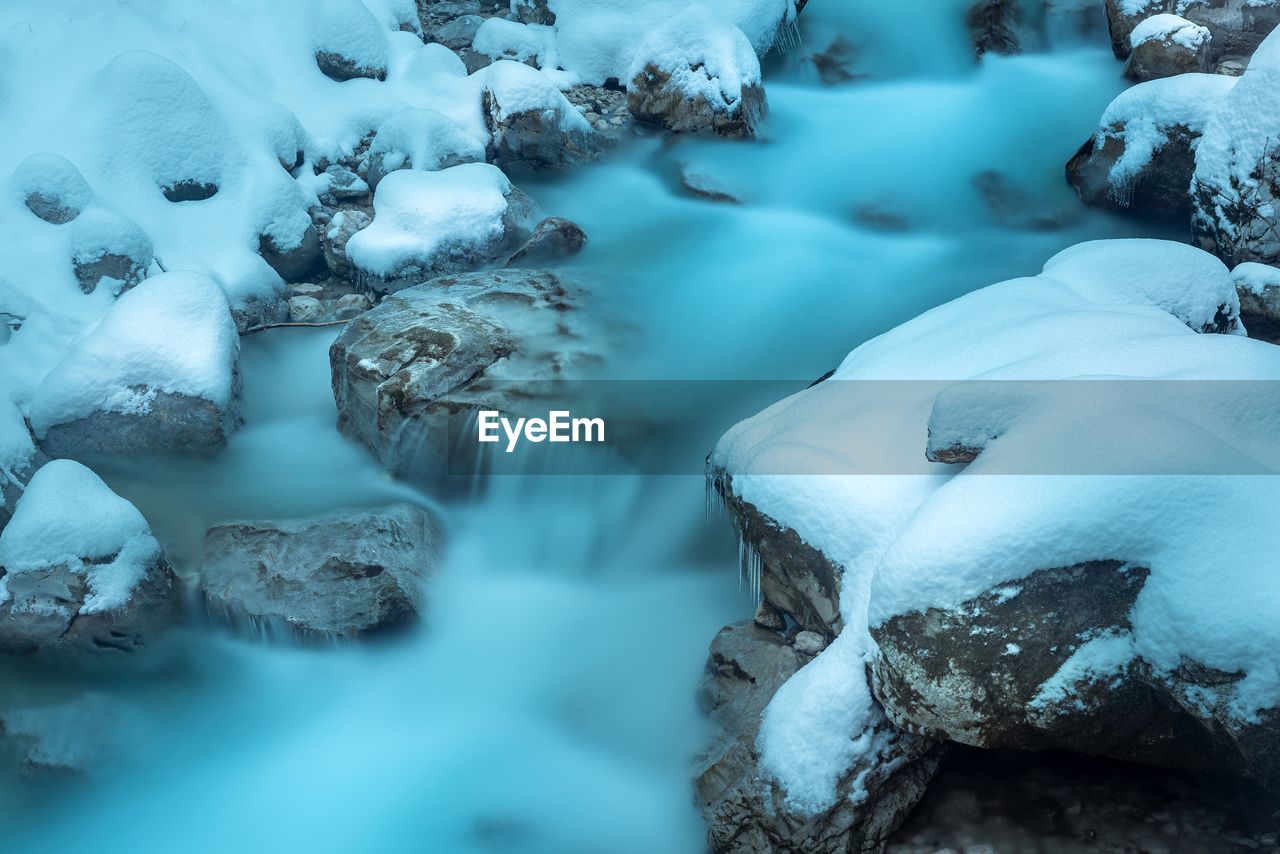 SNOW COVERED ROCKS BY RIVER