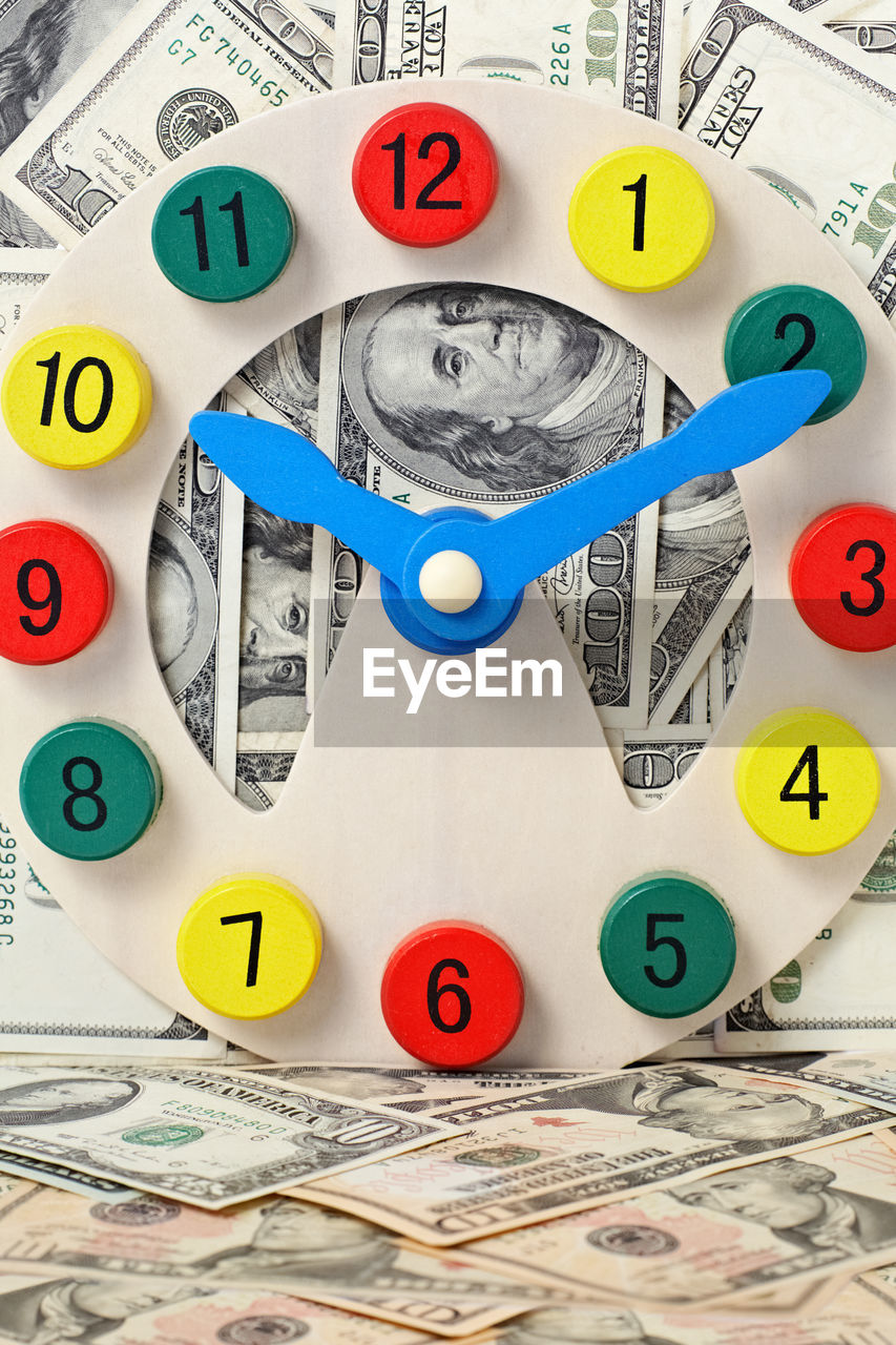 Close-up of multi colored clock and paper currency
