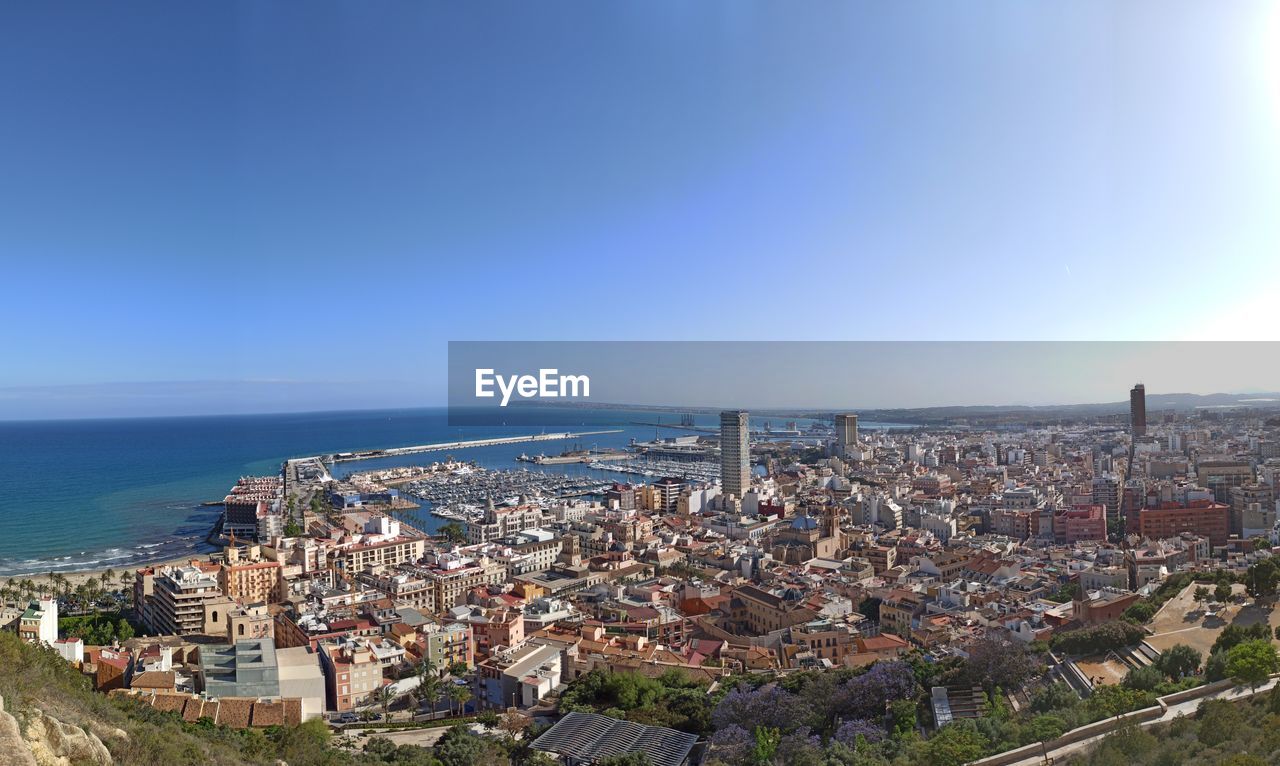 AERIAL VIEW OF TOWNSCAPE BY SEA AGAINST SKY