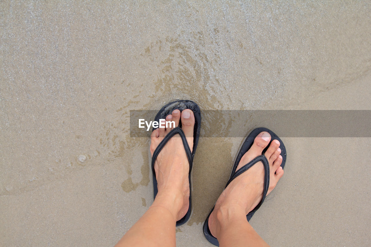 LOW SECTION OF PERSON LEGS ON SAND