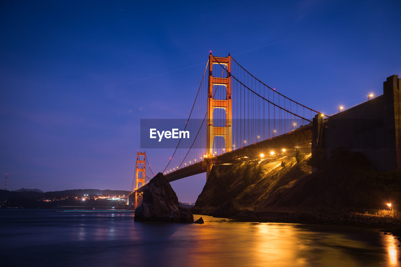 Low angle view of illuminated golden gate bridge over bay at night