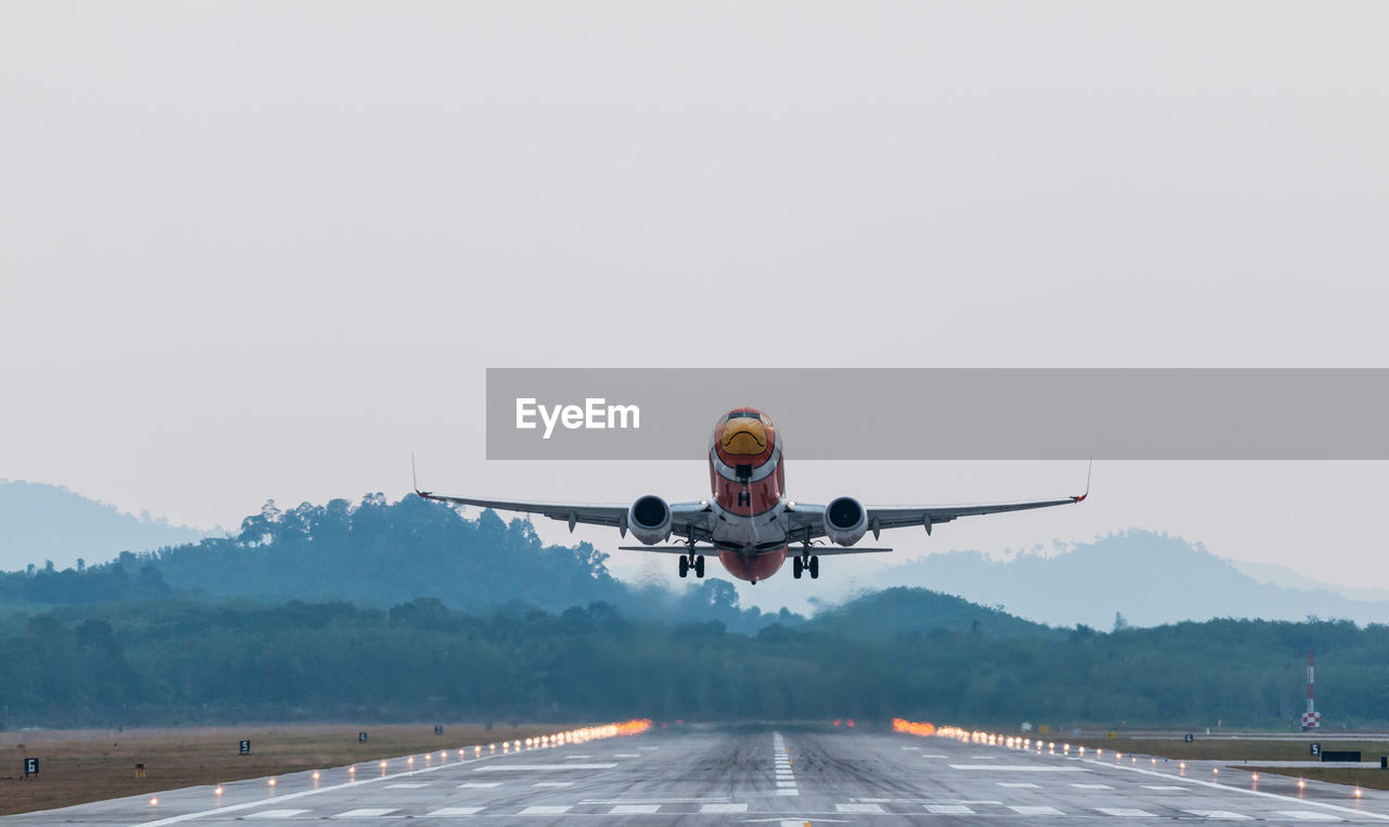Airplane flying on runway against sky